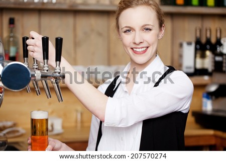 Portrait of young female bartender filling beer in glass at restaurant