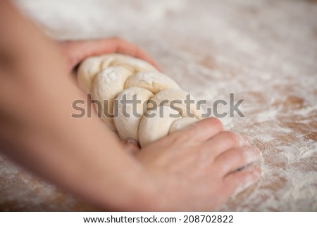 Closeup of female chef\'s hands holding twisted dough at kitchen counter in bakery