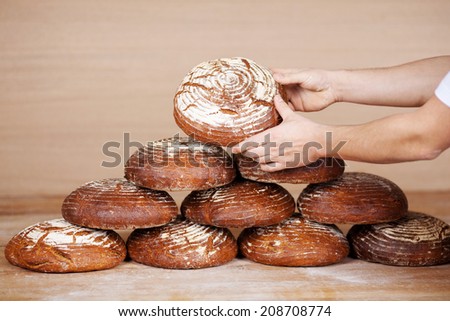 Closeup of saleswoman\'s hands stacking breads on table at bakery