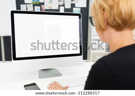 Over the shoulder view of a businesswoman working at a blank computer monitor with a white screen and copyspace