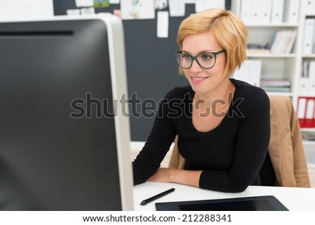 Attractive businesswoman in glasses working in the office sitting at her desk in front of the computer monitor