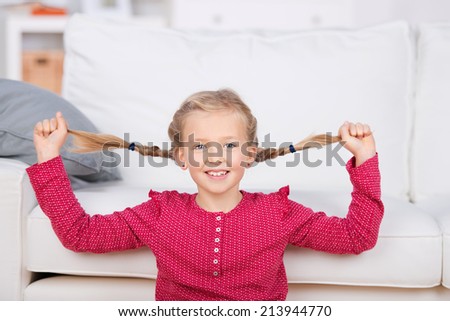 Portrait of a playful girl pulling her pigtails in the living room at home