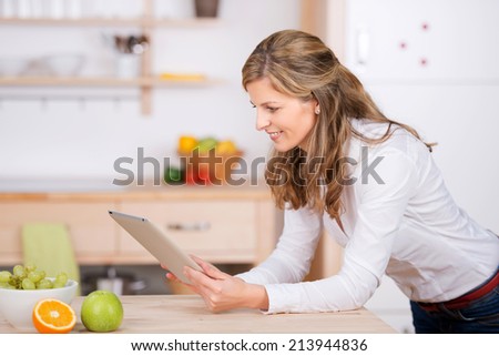smiling woman using digital pad in the kitchen