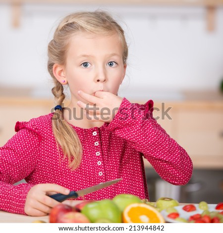 closeup portrait of a little girl cutting fruit for salad in the kitchen