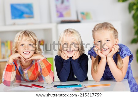 Portrait of happy siblings with drawing papers and pencils leaning on table at home
