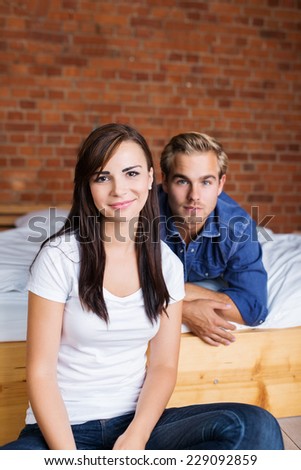 Young Girlfriend and Boyfriend at Bedroom, Looking at Camera on Bricks Wall Background.