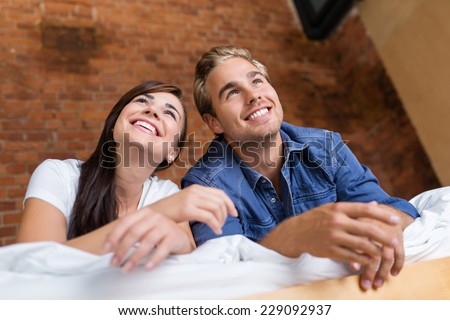 Close up Sweet Smiling Young Couple Lying on White Bed While Looking Upward.