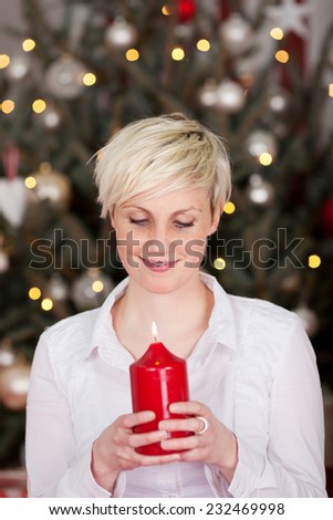 blond woman looking on candle with christmas tree