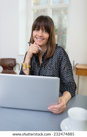Smiling relaxed businesswoman with a happy friendly smile sitting at her desk in the office