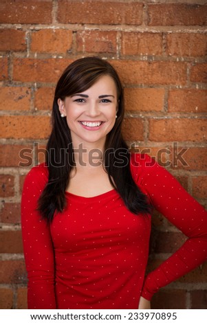 Close up Pretty Smiling Young Woman Wearing Red Long Long Sleeve Shirt on a Brick Wall Background.