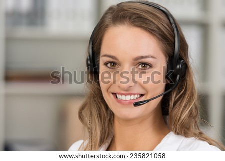 Young attractive woman with a friendly smile wearing a headset for online communication as professional virtual client support or customer service