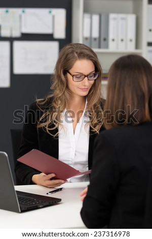 Businesswomen in Black and White Business Suits Having Business Meeting at White Table with Laptop Computer.