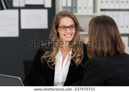 Happy Pretty Corporate Woman with Long Blond Hair Talking Business Matters to Co-worker at the Office.