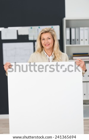 Close up Adult Office Woman Standing Behind Clean White Board at the Office.Captured her While Looking and Smiling at the Camera.