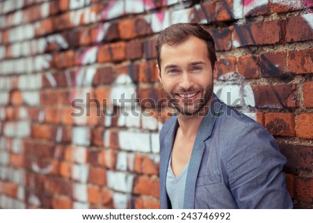 Close up Happy Handsome Man in Trendy Fashion Leaning on Old Brick Wall While Looking at the Camera.