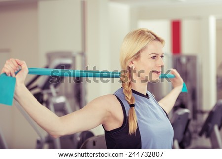 Attractive young blond woman exercising in a gym stretching and toning her muscles in a health and fitness concept