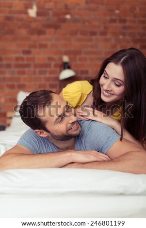 Playful affectionate couple relaxing at home lying on the bed looking at each other with a loving smile