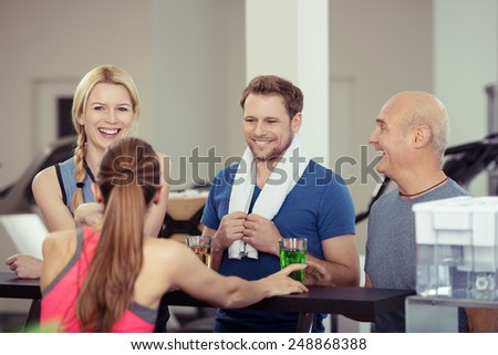 Happy group of diverse friends enjoying refreshments at the gym after a workout chatting and laughing