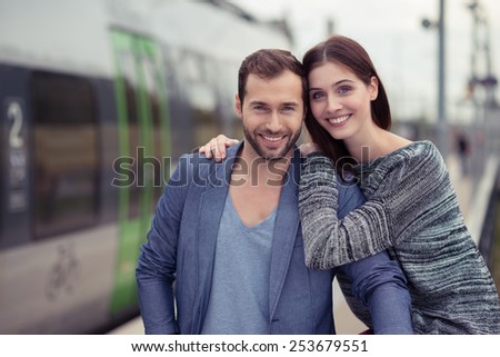 Affectionate couple posing arm in arm outdoors in an urban environment smiling happily at the camera