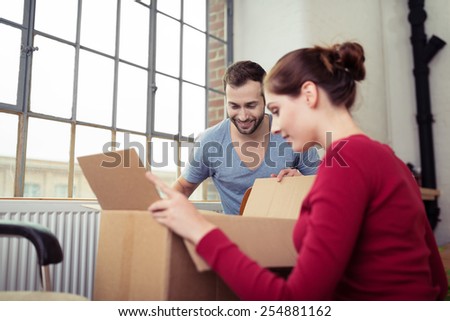 Newly Married White Couple Opening Cardboard Boxes at their New Home.