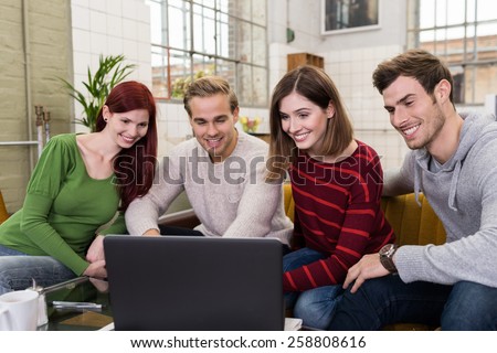 Group of Happy Young White Friends Watching Something at Laptop Computer at the Living Room Area.