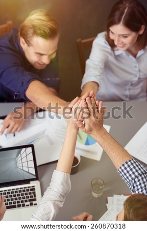 Close up Aerial View of Group of Friends Holding Hands Together at the Center While Having a Meeting at the Table.