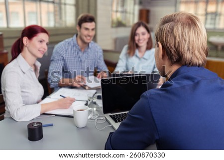 Close up Rear View of Young Blond Man Discussing to the Group at the Table.
