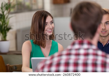 Sitting Pretty Young Woman Wearing Green Sleeveless Outfit Talking to Friends at the Table.