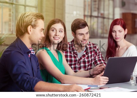Group of Young Friends Discussing a Project While Sitting at the Table with Laptop Computer.