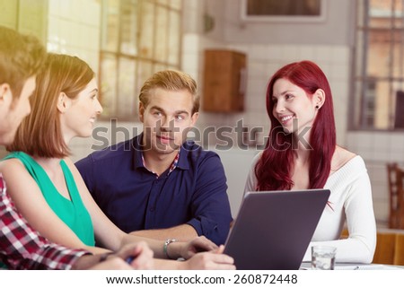Group of Young White Friends Talking at the Table with Laptop Computer Inside a Building.