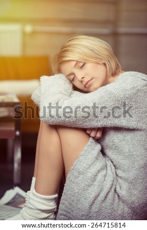 Pretty young woman taking a relaxing break sitting with her head on her knees and eyes closed on the floor