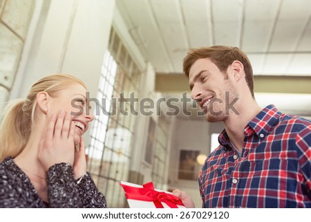 Close up Handsome Young Boyfriend Offering Presents to his Pretty Blond Girlfriend with Happy Facial Expression.