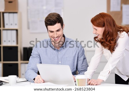 Happy Young Business Couple Watching Something at Laptop Computer on Top of the Office Table.