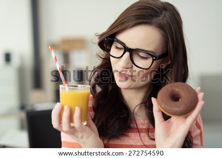 Close up Pretty Young Woman with Eyeglasses Holding a Glass of Orange Juice and Chocolate Doughnut