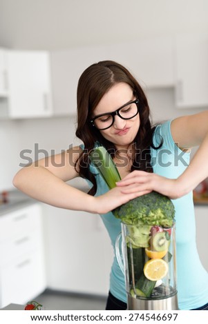 Young Woman Wearing Eyeglasses Packing Blender Full of Fruits and Vegetables While Making a Health Shake