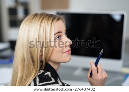 Profile view of an attractive young businesswoman looking up with a smile with her pen in her hand and an attentive expression as she looks at a work colleague
