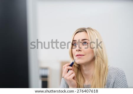 Close up Thoughtful Pretty Young Woman with Blond Hair, Holding a Pen and Looking Afar While Sitting at her Worktable.