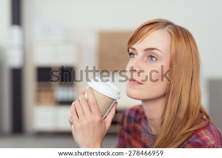 Close up Thoughtful Young Blond Woman Holding a Cup of Coffee with Both Hands While Looking Up.