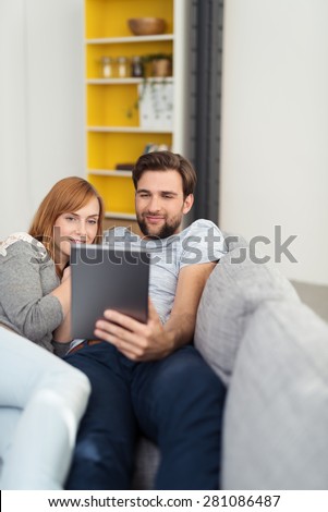 Young man and woman reading a tablet-pc as they relax together on a sofa at home enjoying a relaxing day