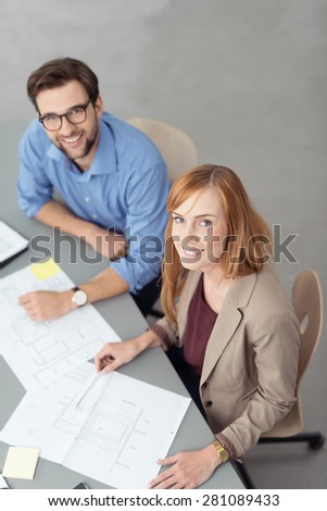Young Smiling Co-Workers Looking Up at Camera While Discussing Paperwork in Business Meeting