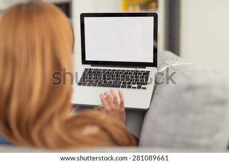 Woman with Red Hair Sitting on Sofa with Laptop Computer, Perspective from Behind Over Shoulder Looking at Blank Computer Screen