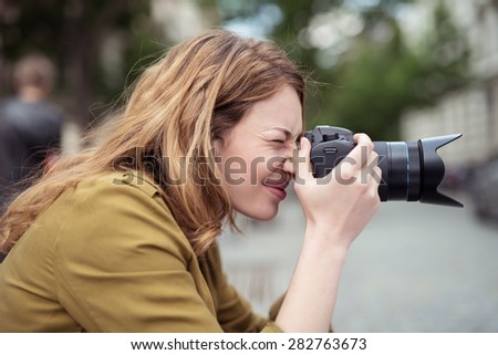 Close up Side View of a Teen Blond Girl Photographer Shooting with DSLR Photo Camera at the Street.