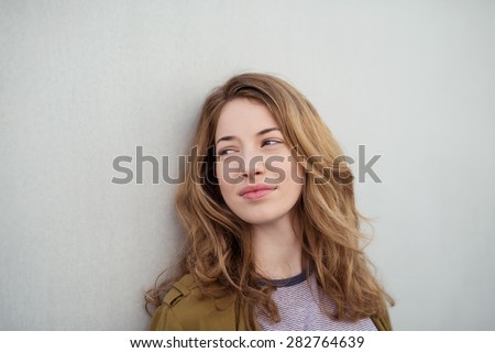 Close up Pensive Young Brown-Haired Woman Leaning on the White Wall While Looking Into Distance.
