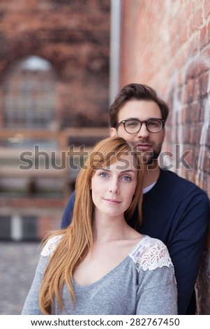 Close up Smiling Young Couple Standing Beside Old Outside Brick Wall While Looking at the Camera.