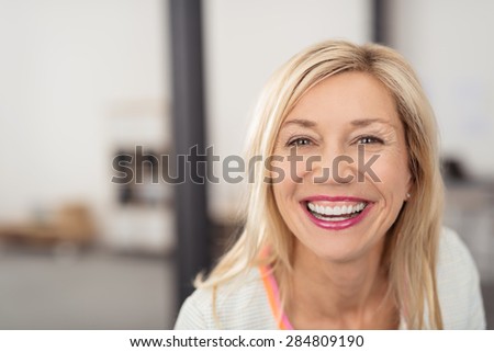 Laughing middle-aged blond woman with beaming smile looking directly into the camera