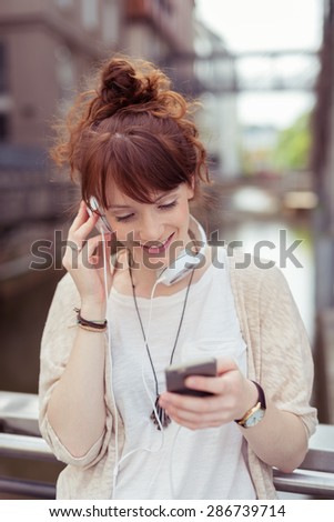 Attractive Girl Enjoying the Music on her Mobile Phone Using Headphone While Resting at the Railings of the Bridge.