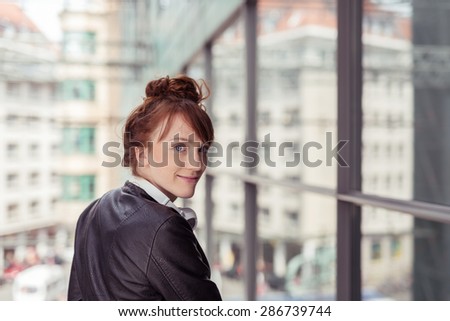 Pretty Young Woman, Wearing Black Leather Jacket, Walking at the City While Looking at the Camera Behind Her.