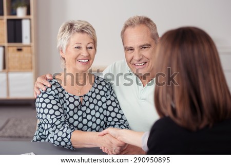 Happy Senior Couple Shaking Hands with Female Financial Agent at the Table While Making a Deal.