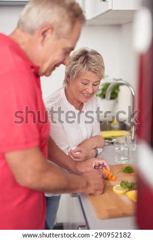 Smiling Wife Watching Over her Husband While Slicing the Fresh Food Ingredients for their Dinner at the Kitchen.