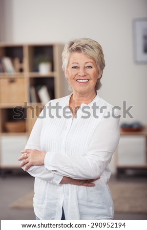 Portrait of a Confident Middle Aged Woman in White Long-Sleeved Shirt, Smiling at the Camera with Arms Crossing Over her Stomach.